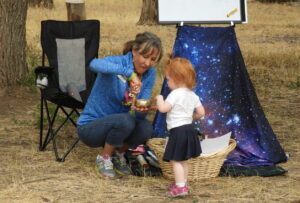 Librarian Amy Holzworth at outdoor storytime with a little girl