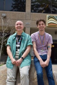 two men smiling in front of a library