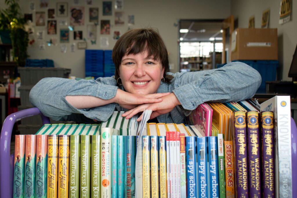 woman smiling on top of a stack books