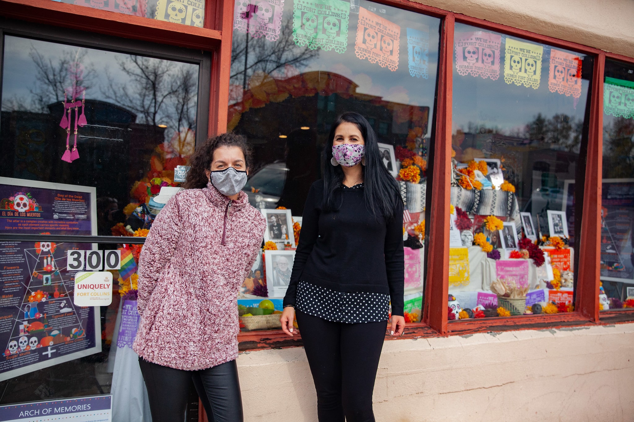 two latina women standing in front of a store window