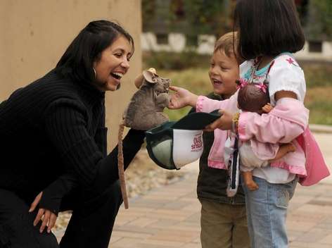 latina woman smiling with an animal puppet and two children