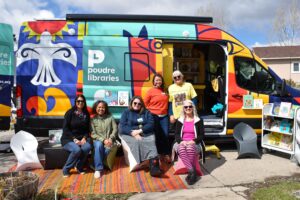 group of women smiling in front of a colorful van