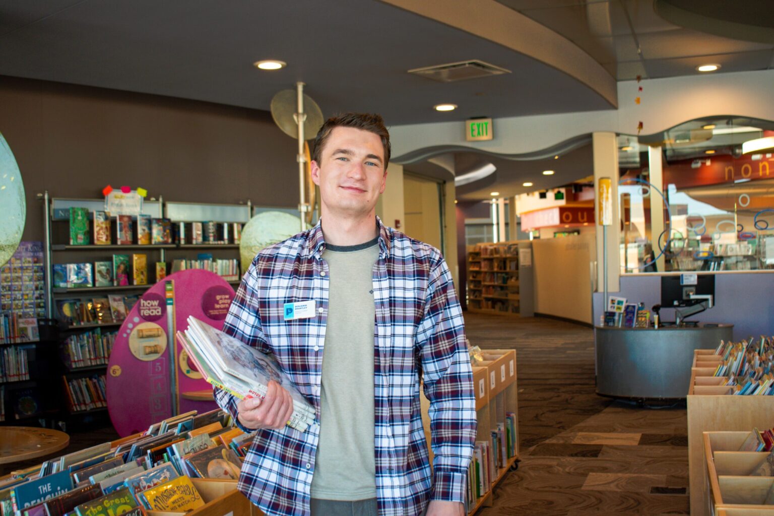 white man holding books in a library