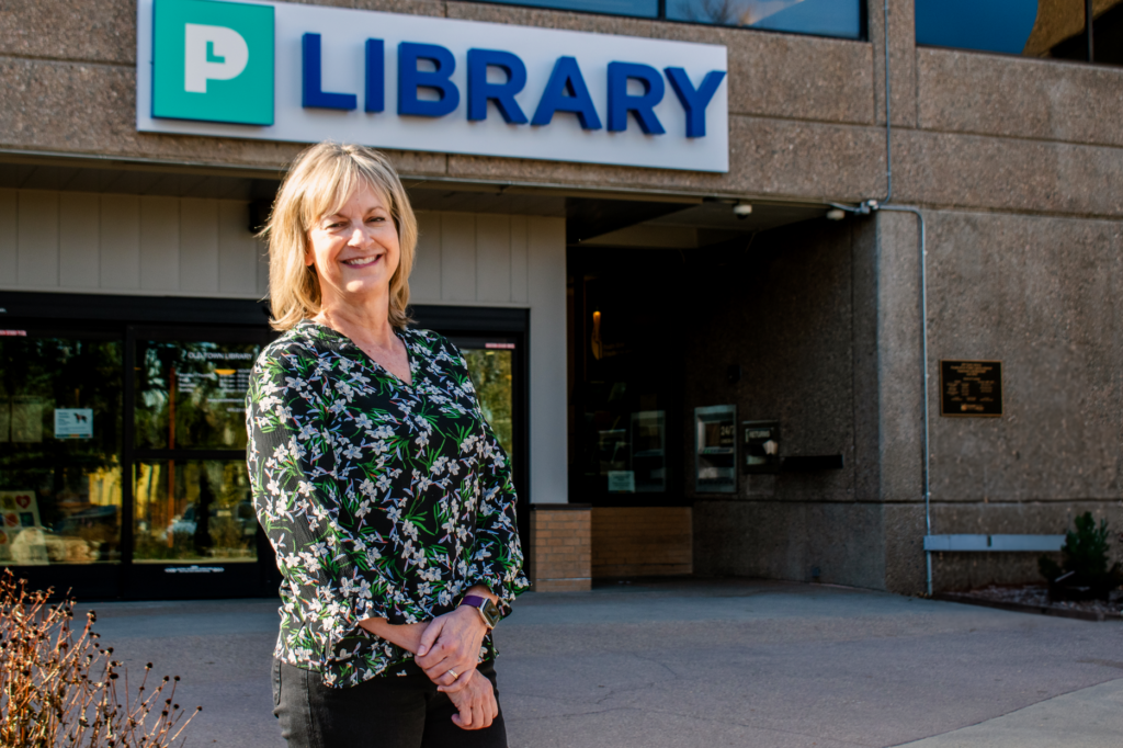 white woman smiling in front of a library